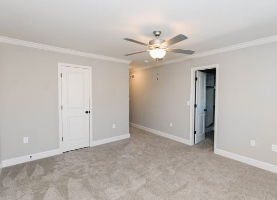 a living room with a ceiling fan and a large room with walls and doors