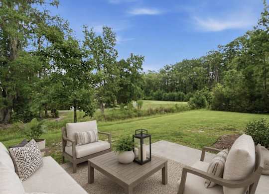 A patio with a table and chairs overlooking a grassy area.