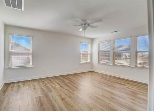 an empty bedroom with hardwood floors and a ceiling fan