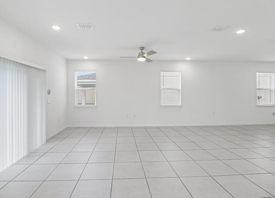 A spacious room with white walls and a ceiling fan.