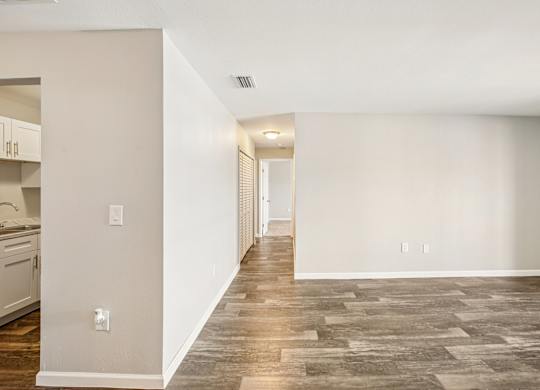 A long hallway with a kitchen on the left and a door at the end.