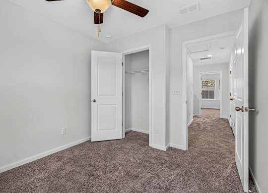 A room with a carpeted floor and a ceiling fan.