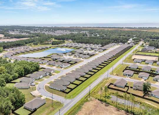 A bird's eye view of a residential area with houses, roads, and greenery.