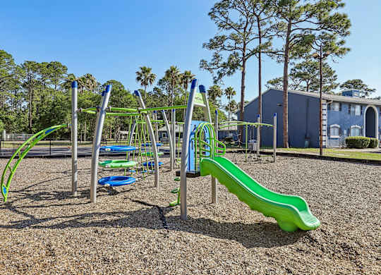 A playground with a green slide and a blue and green climbing frame.