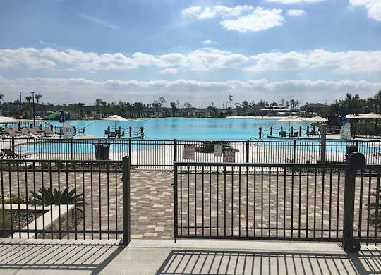 Three-Bedroom Apartments in Humble, TX - Edgewater at the Lagoon - Expansive Lagoon-Style Pool with Umbrellas and Lounge Seats.