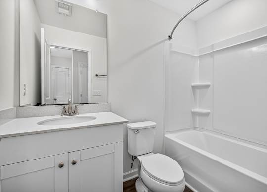 A white bathroom with a toilet, sink, and bathtub.