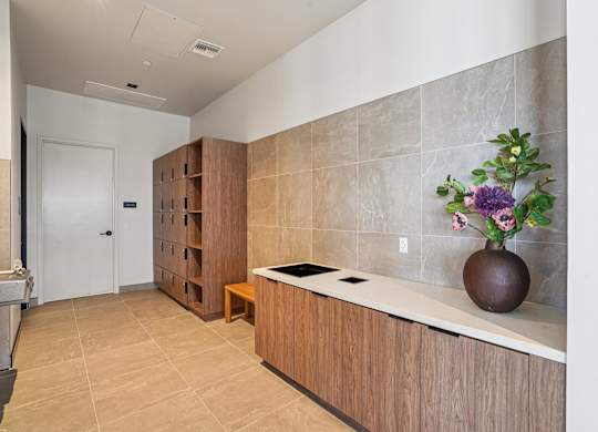 A kitchen with a brown vase of flowers on the counter.
