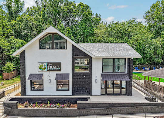 A white building with a black roof and a green sign that says
