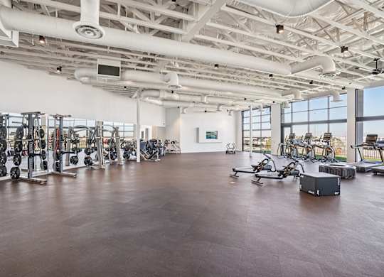A spacious gym with a variety of equipment and a large mirror on the wall.