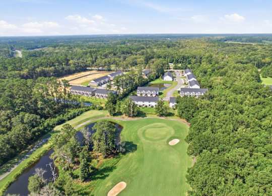 A golf course with a clubhouse and several houses in the background.