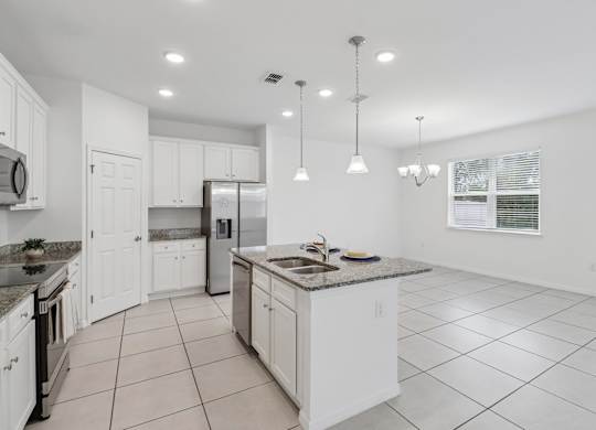 A kitchen with white cabinets and a granite countertop.