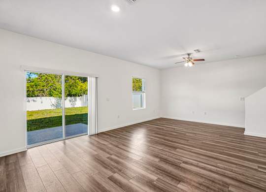 A room with a ceiling fan and sliding glass doors.