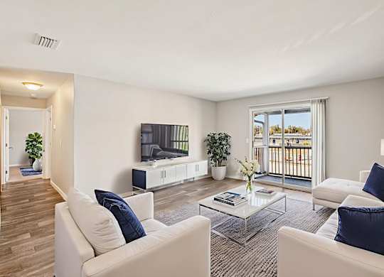 A living room with white furniture and a large window.