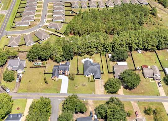 A bird's eye view of a residential area with houses, roads, and a lake.
