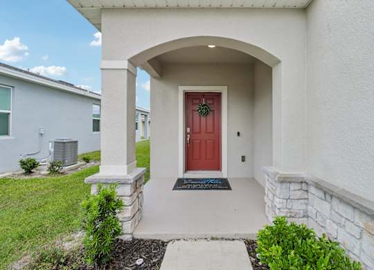A house with a red door and a stone pillar.