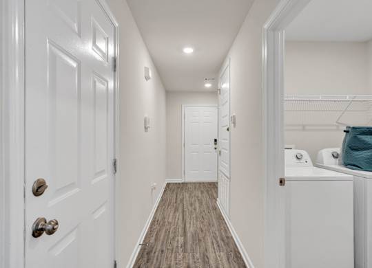 A hallway with white doors and a wooden floor.