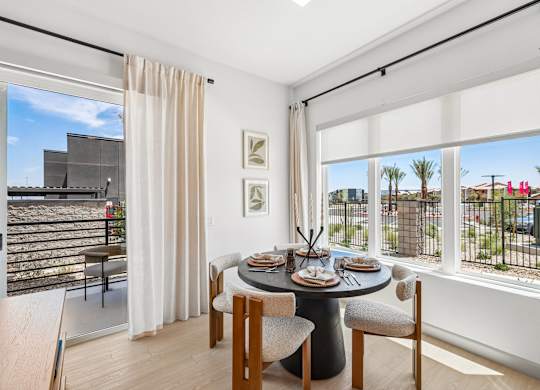 A dining room with a table set for two and a view of the outside.