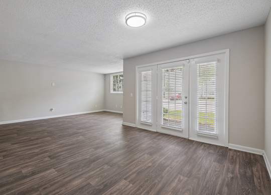 A room with wooden flooring and a window with white shutters.