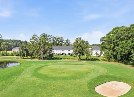 A golf course with a green and a sand trap.