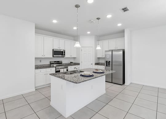 A modern kitchen with a granite countertop and stainless steel appliances.