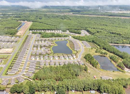 A bird's eye view of a residential area with a lake and greenery.