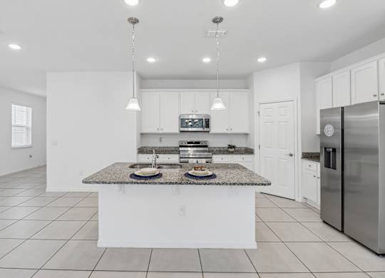 A modern kitchen with a granite countertop and stainless steel appliances.