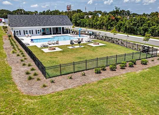 A black fence surrounds a pool and a house.