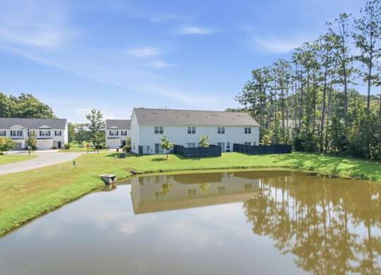 A serene landscape with a house, trees, and a pond.