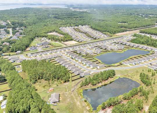 A bird's eye view of a residential area with a lake and greenery.