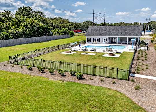 A pool surrounded by a black fence with a building in the background.