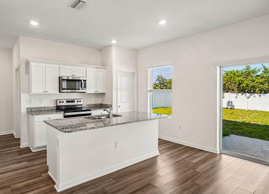 A kitchen with white cabinets and a granite countertop.
