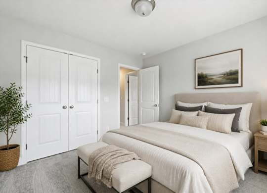 A bedroom with a large bed, a bench, and a potted plant.