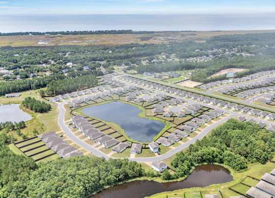 A bird's eye view of a residential area with houses, roads, and a lake.