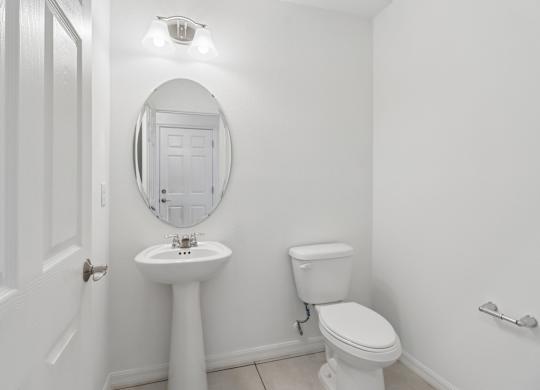 A white bathroom with a toilet, sink, and mirror.