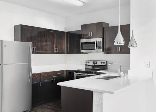 A modern kitchen with a refrigerator, microwave, oven, and cabinets.