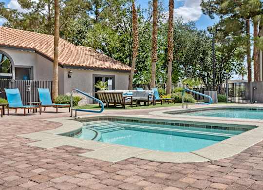 A pool surrounded by a brick patio and a house in the background.