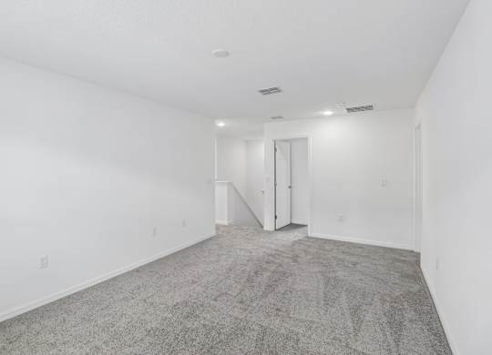 A spacious room with a carpeted floor and white walls.