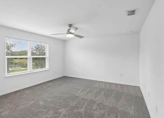 A room with a ceiling fan and carpeted floor.