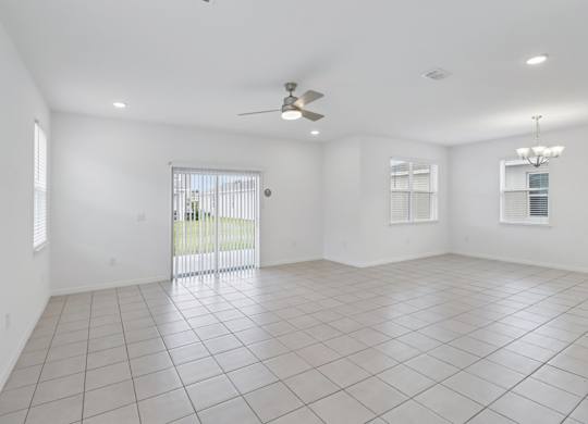 A spacious room with a ceiling fan and sliding glass doors.