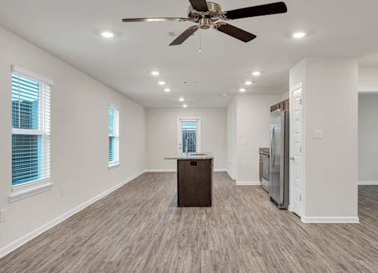 A spacious room with a ceiling fan and wooden flooring.