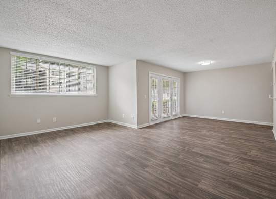 A room with wooden flooring and a window with blinds.
