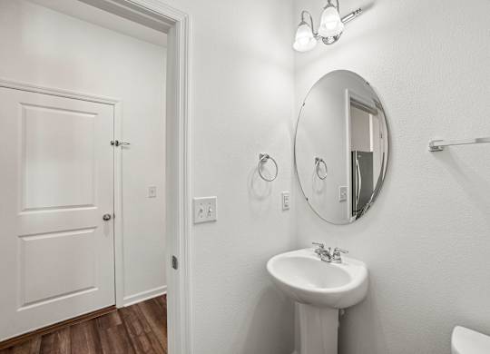 A white bathroom with a sink and mirror.