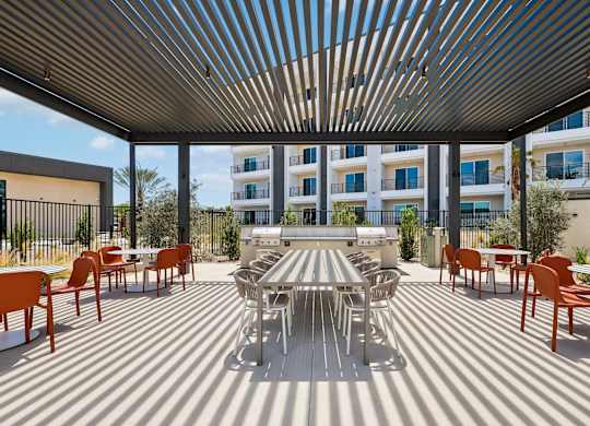A patio with a table and chairs is covered by a striped awning.