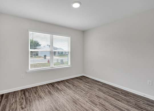 A room with a window and wooden flooring.