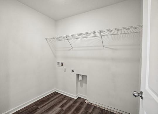 A white wall with a door and a shelf.
