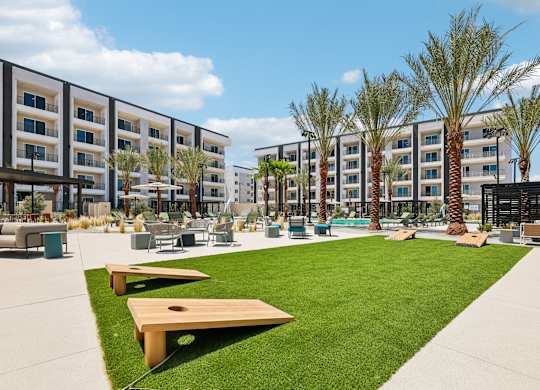 A sunny day at a modern apartment complex with a grassy area and palm trees.