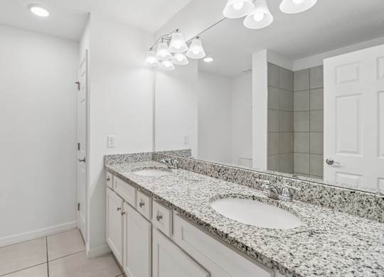 A bathroom with granite countertops and a large mirror.