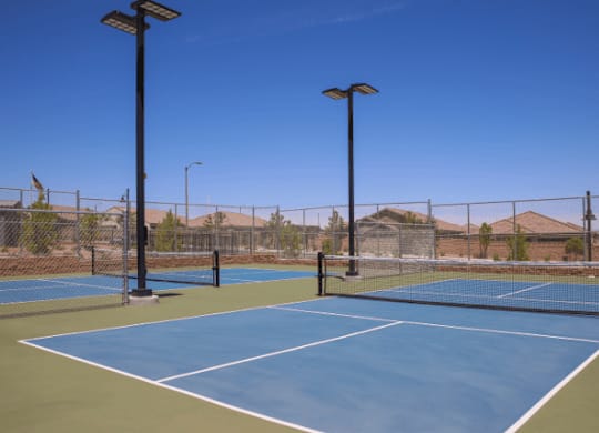 A tennis court with a net and two light poles.