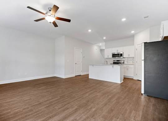 an empty living room and kitchen with a ceiling fan