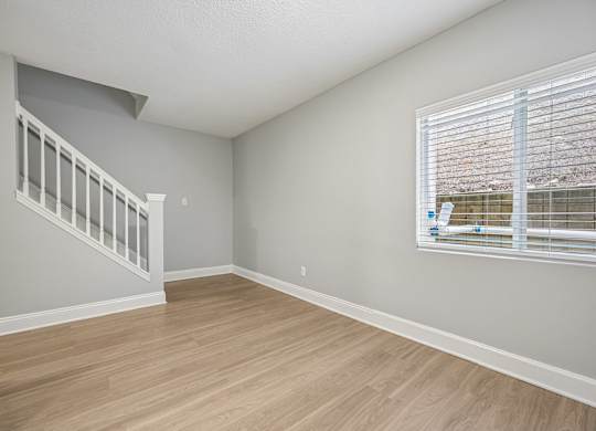 A room with a staircase and a window with blinds.